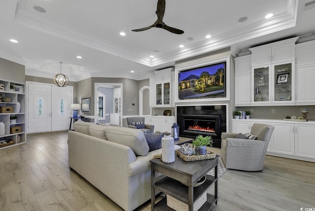 1108 Surf Pointe Dr, North Myrtle Beach, SC 29582 - living room featuring a raised ceiling, light wood finished floors, crown molding, a glass covered fireplace, and ceiling fan