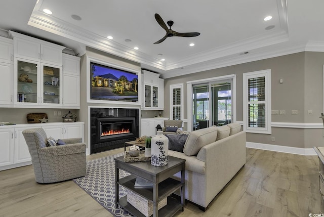 1108 Surf Pointe Dr, North Myrtle Beach, SC 29582 - living area with a tray ceiling, light wood-style flooring, a ceiling fan, ornamental molding, and a glass covered fireplace