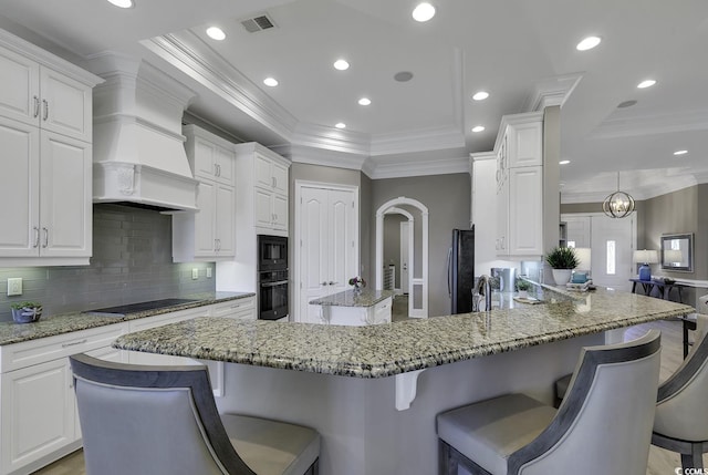 1108 Surf Pointe Dr, North Myrtle Beach, SC 29582 - kitchen featuring black appliances, a raised ceiling, a kitchen island, backsplash, and custom range hood