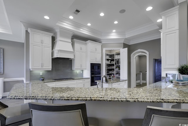 1108 Surf Pointe Dr, North Myrtle Beach, SC 29582 - kitchen featuring black appliances, premium range hood, ornamental molding, light stone counters, and white cabinetry