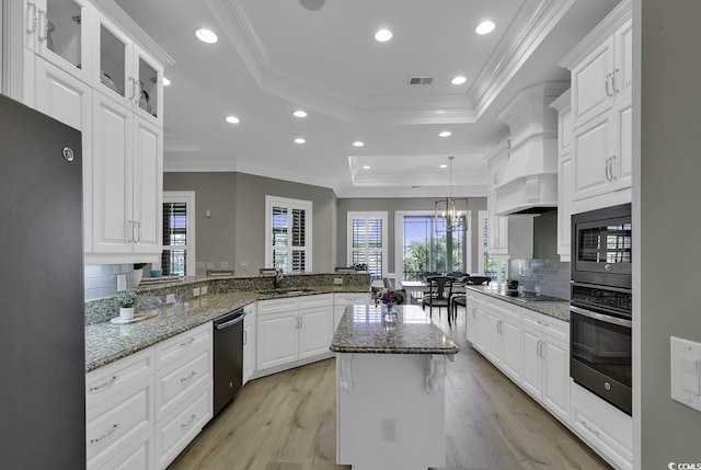 1108 Surf Pointe Dr, North Myrtle Beach, SC 29582 - kitchen with stainless steel appliances, a tray ceiling, a sink, a peninsula, and custom range hood