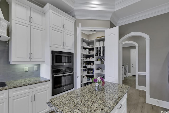 1108 Surf Pointe Dr, North Myrtle Beach, SC 29582 - kitchen featuring oven, arched walkways, light wood-type flooring, decorative backsplash, and ornamental molding
