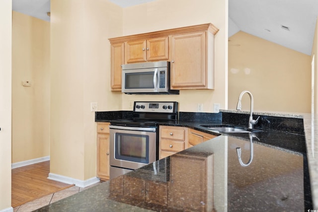 2384 Covington Dr, Myrtle Beach, SC 29579 - kitchen with stainless steel appliances, a sink, dark stone counters, light brown cabinets, and lofted ceiling
