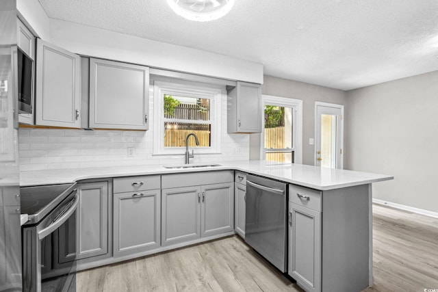 315 73rd Ave N Unit 2, Myrtle Beach, SC 29572 - kitchen featuring appliances with stainless steel finishes, gray cabinetry, a peninsula, light wood-style floors, and a textured ceiling