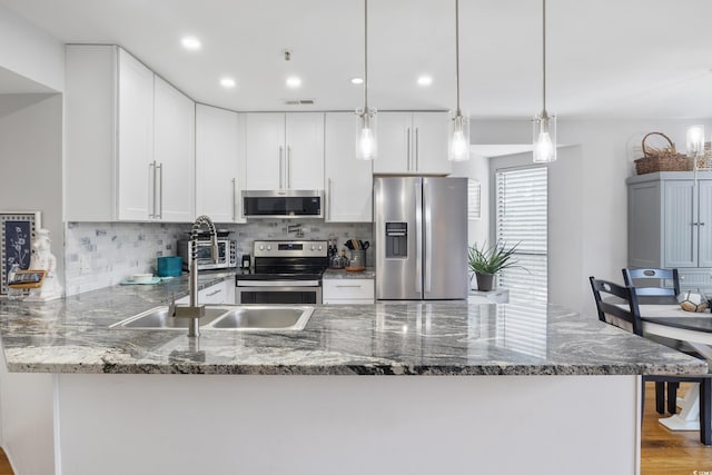 1101 Possum Trot Rd Unit D201, North Myrtle Beach, SC 29582 - kitchen with appliances with stainless steel finishes, a peninsula, decorative backsplash, dark stone counters, and white cabinetry