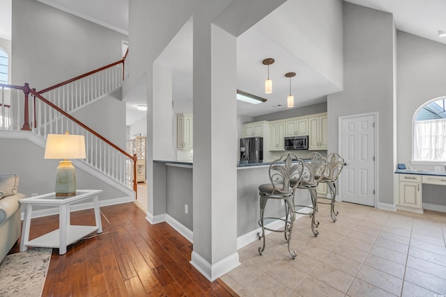 4232 Pointer Ct, Myrtle Beach, SC 29579 - kitchen with cream cabinets, stainless steel appliances, a high ceiling, a kitchen breakfast bar, and baseboards