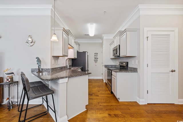 172 Ella Kinley Cir Unit 101, Myrtle Beach, SC 29588 - kitchen featuring appliances with stainless steel finishes, a kitchen breakfast bar, a peninsula, wood finished floors, and dark stone counters