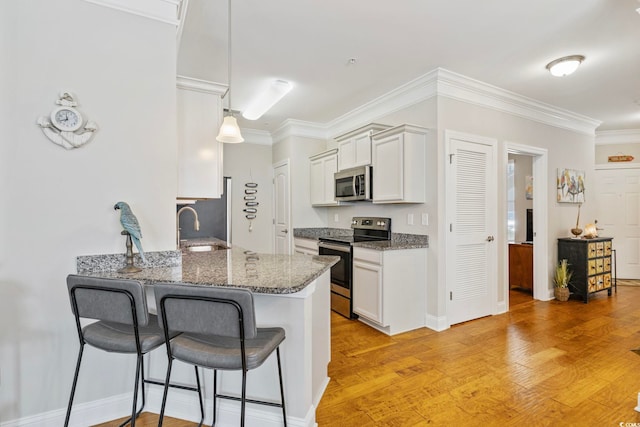 172 Ella Kinley Cir Unit 101, Myrtle Beach, SC 29588 - kitchen featuring appliances with stainless steel finishes, a kitchen breakfast bar, dark stone counters, ornamental molding, and white cabinetry