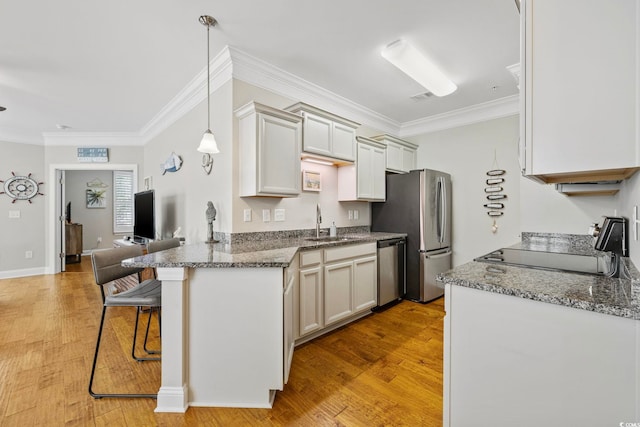 172 Ella Kinley Cir Unit 101, Myrtle Beach, SC 29588 - kitchen with stainless steel appliances, a sink, a breakfast bar, ornamental molding, and light wood-style floors