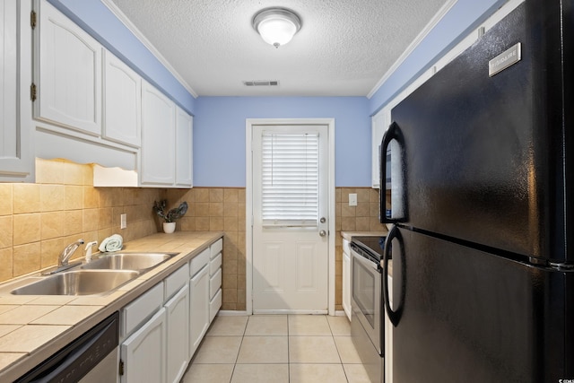 403 75th Ave N Unit C, Myrtle Beach, SC 29572 - kitchen with stainless steel appliances, tile countertops, a sink, white cabinetry, and a textured ceiling