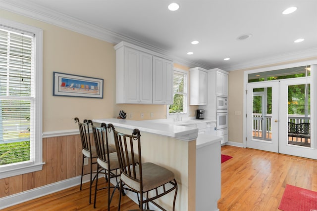 141 Cayman Loop, Pawleys Island, SC 29585 - kitchen with wall oven, ornamental molding, a breakfast bar, french doors, and white cabinetry