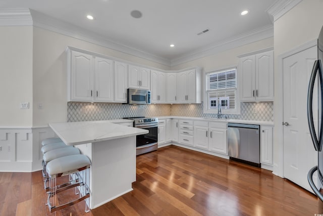 1619 Eastover Ln, North Myrtle Beach, SC 29582 - kitchen with appliances with stainless steel finishes, a sink, a peninsula, white cabinets, and crown molding