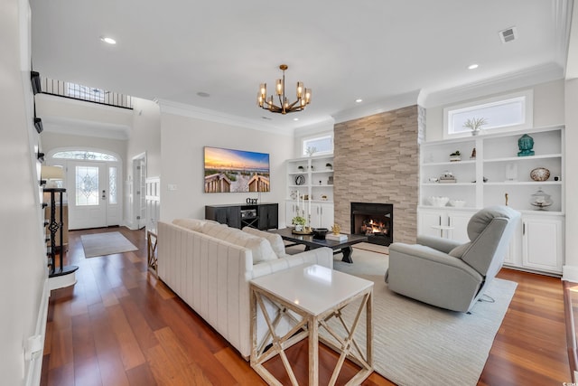 1619 Eastover Ln, North Myrtle Beach, SC 29582 - living room with a chandelier, a large fireplace, wood finished floors, ornamental molding, and built in shelves