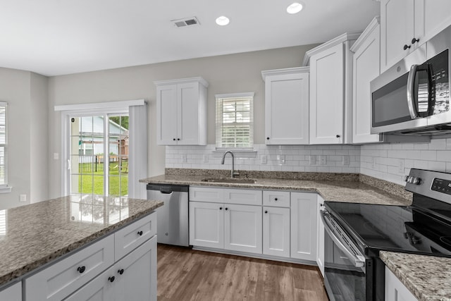 104 Browns Hollow Ct, Loris, SC 29569 - kitchen with appliances with stainless steel finishes, white cabinetry, light wood-style floors, tasteful backsplash, and recessed lighting