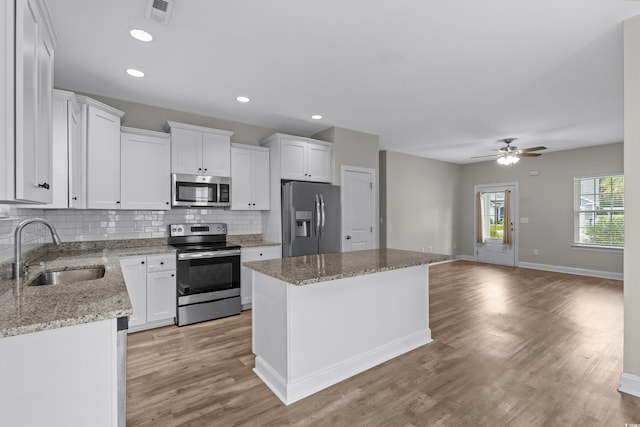 104 Browns Hollow Ct, Loris, SC 29569 - kitchen with appliances with stainless steel finishes, a kitchen island, backsplash, white cabinets, and a ceiling fan