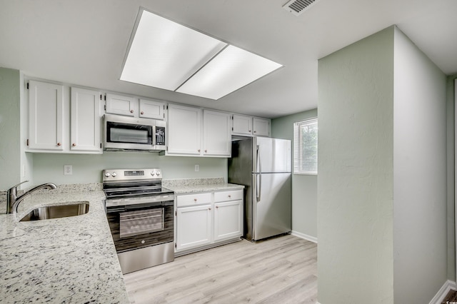 1200 5th Ave N Unit 1207, Surfside Beach, SC 29575 - kitchen with appliances with stainless steel finishes, a sink, light wood-style floors, light stone counters, and white cabinetry