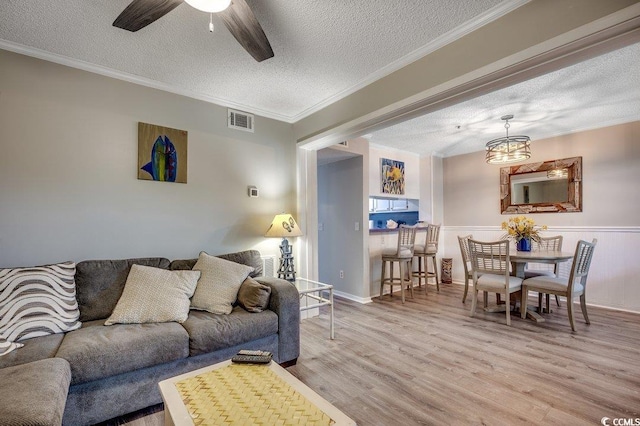 211 N Hillside Dr Unit 204, North Myrtle Beach, SC 29582 - living room with a textured ceiling, wood finished floors, a ceiling fan, crown molding, and a chandelier