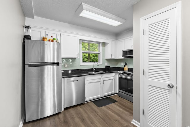 1356 Glenns Bay Rd Unit A202, Surfside Beach, SC 29575 - kitchen with appliances with stainless steel finishes, white cabinets, dark countertops, decorative backsplash, and dark wood finished floors