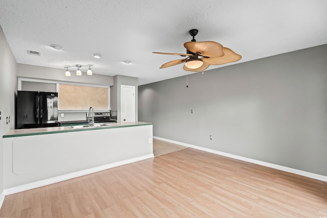 4101 Pinehurst Cir Unit Aa-3, Little River, SC 29566 - kitchen with freestanding refrigerator, a sink, light wood-type flooring, a ceiling fan, and a textured ceiling
