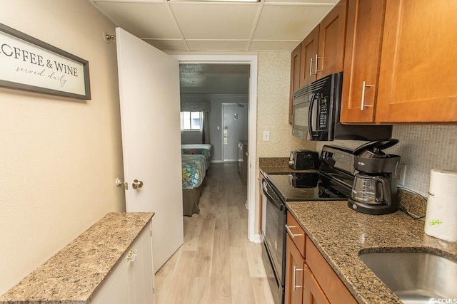 1105 S Ocean Blvd Unit 932, Myrtle Beach, SC 29577 - kitchen with electric range, black microwave, brown cabinets, light wood finished floors, and stone counters