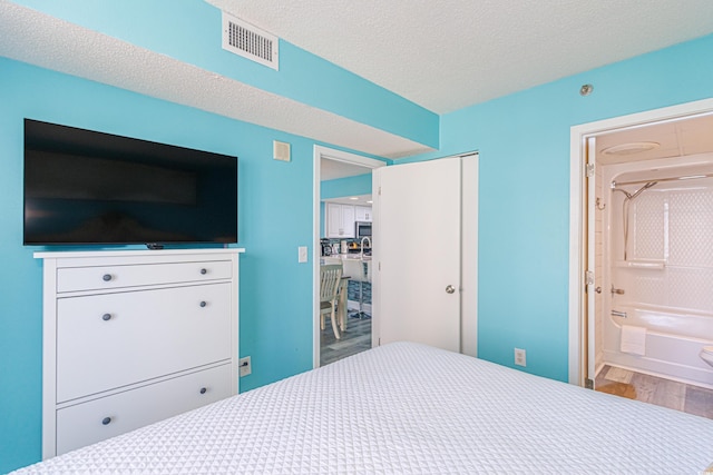 161 Sea Watch Dr Unit 601, Myrtle Beach, SC 29572 - bedroom with wood finished floors, ensuite bath, a closet, and a textured ceiling