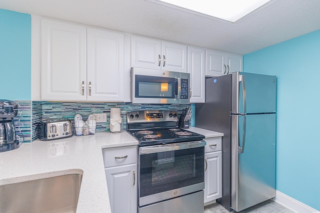 161 Sea Watch Dr Unit 601, Myrtle Beach, SC 29572 - kitchen featuring stainless steel appliances, white cabinetry, tasteful backsplash, and light stone counters