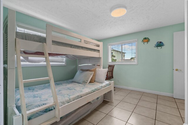 5409 N Ocean Blvd Unit 100, North Myrtle Beach, SC 29582 - bedroom featuring light tile patterned floors, a textured ceiling, and baseboards