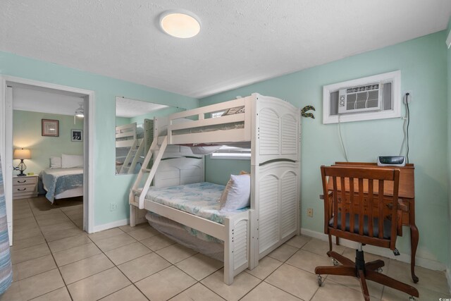 5409 N Ocean Blvd Unit 100, North Myrtle Beach, SC 29582 - bedroom with a wall unit AC, light tile patterned flooring, a textured ceiling, and baseboards