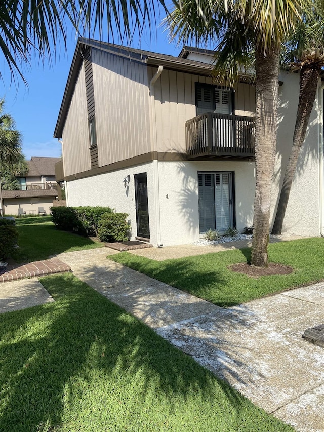 10200 Lake Shore Dr Unit 4, Myrtle Beach, SC 29572 - view of front of house with a balcony, a front lawn, and stucco siding