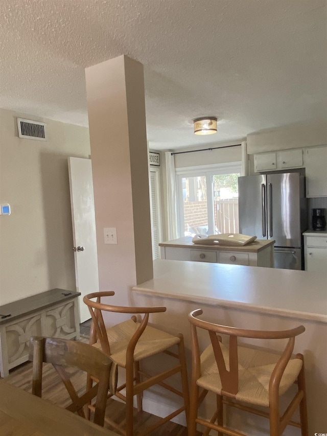 10200 Lake Shore Dr Unit 4, Myrtle Beach, SC 29572 - kitchen featuring freestanding refrigerator, a breakfast bar area, a textured ceiling, and light countertops
