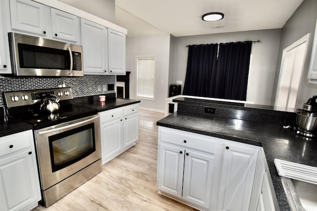 126 Clovis Cir, Myrtle Beach, SC 29579 - kitchen with stainless steel appliances, dark countertops, white cabinetry, light wood-style floors, and decorative backsplash
