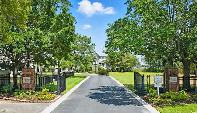 191 Grackle Ln, Pawleys Island, SC 29585 - view of asphalt road featuring street lights, curbs, and a gated entry