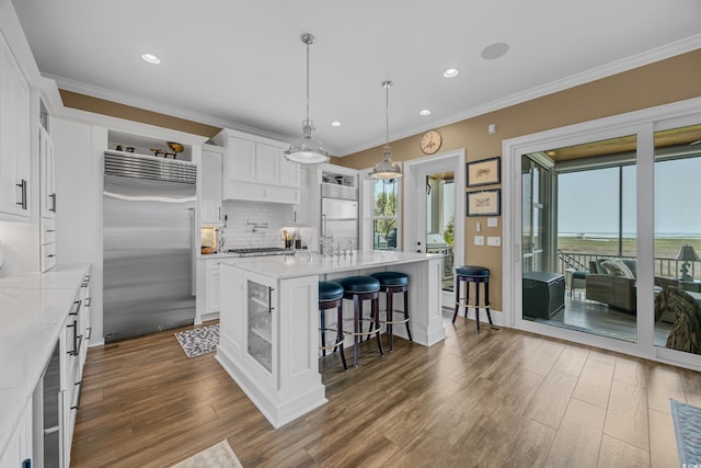 191 Grackle Ln, Pawleys Island, SC 29585 - kitchen with built in fridge, dark wood-style flooring, backsplash, white cabinetry, and a kitchen bar