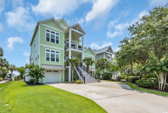 191 Grackle Ln, Pawleys Island, SC 29585 - raised beach house with board and batten siding, a balcony, concrete driveway, a front yard, and a garage