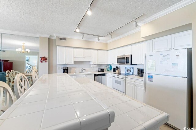 341 S Dunes Dr Unit C-34, Pawleys Island, SC 29585 - kitchen featuring appliances with stainless steel finishes, tile counters, rail lighting, a textured ceiling, and a sink