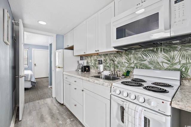 2001 S Ocean Blvd Unit 815, Myrtle Beach, SC 29577 - kitchen featuring white appliances, white cabinets, light wood-type flooring, and light stone counters