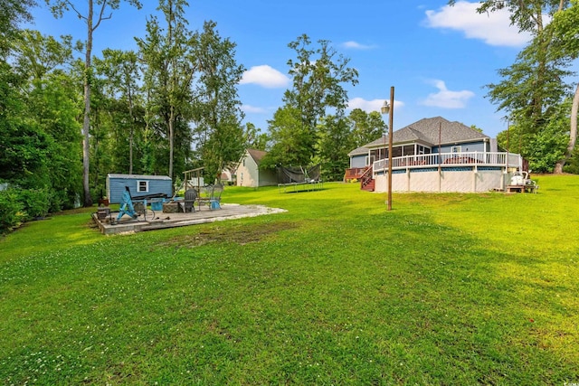 1051 Academy Dr, Conway, SC 29526 - view of green lawn with a trampoline, an outdoor pool, an outbuilding, a patio area, and a wooden deck