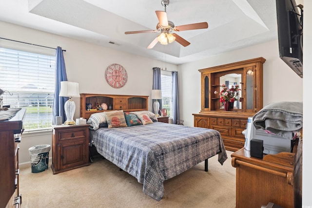 1068 Lizzie Ln, Surfside Beach, SC 29575 - bedroom featuring a tray ceiling, light carpet, multiple windows, and a ceiling fan