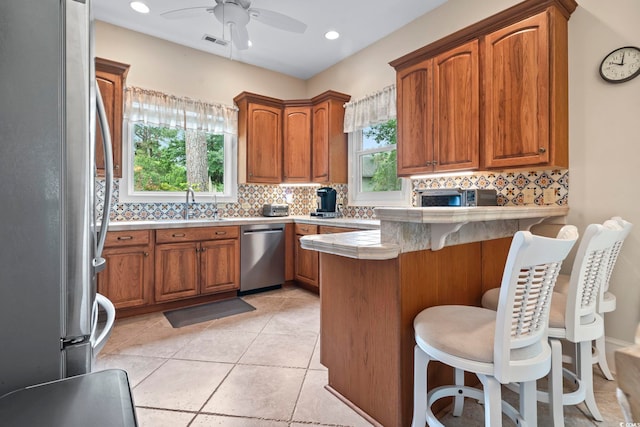 1501 Harbor Dr, North Myrtle Beach, SC 29582 - kitchen with stainless steel appliances, a peninsula, backsplash, brown cabinetry, and recessed lighting