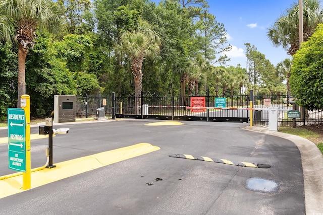 9776 Leyland Dr Unit 2, Myrtle Beach, SC 29572 - view of asphalt street featuring a gated entry, a gate, view of wooded area, and curbs