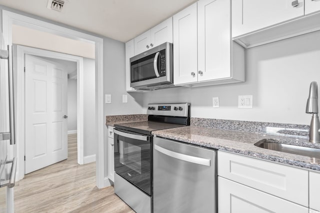 601 Mitchell Dr Unit 207, Myrtle Beach, SC 29577 - kitchen featuring stainless steel appliances, white cabinetry, light stone counters, and light wood-style floors