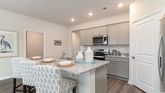 2750 Riverboat Way, Conway, SC 29526 - kitchen featuring stainless steel appliances, gray cabinetry, dark wood finished floors, a kitchen breakfast bar, and a kitchen island with sink