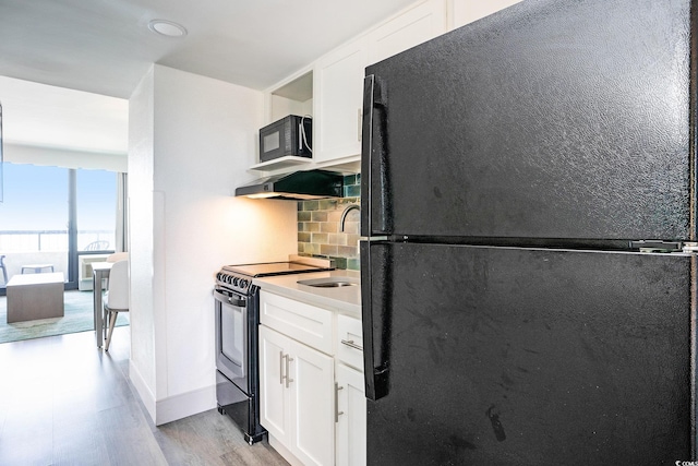 2401 S Ocean Blvd Unit 557, Myrtle Beach, SC 29577 - kitchen featuring black appliances, backsplash, light wood-style floors, white cabinets, and light countertops