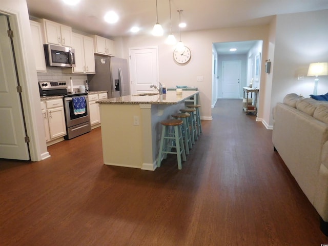 401 Quinta St, Longs, SC 29568 - kitchen featuring stainless steel appliances, dark wood-style floors, white cabinetry, a kitchen breakfast bar, and a center island with sink