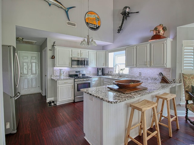 1635 Southwood Dr, Surfside Beach, SC 29575 - kitchen featuring stainless steel appliances, high vaulted ceiling, a peninsula, tasteful backsplash, and light stone countertops