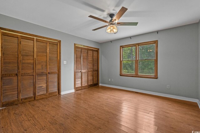 124 Wicklow Way, Pawleys Island, SC 29585 - unfurnished bedroom with two closets, baseboards, wood finished floors, and a ceiling fan