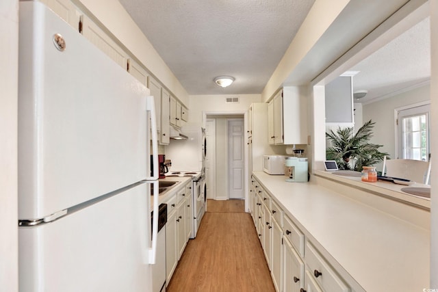 211 76th Ave N Unit A3, Myrtle Beach, SC 29572 - kitchen featuring white appliances, a textured ceiling, light countertops, light wood-style flooring, and under cabinet range hood