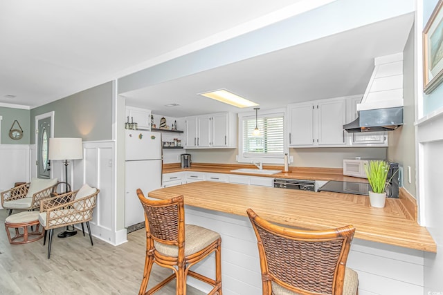 4309 Beverly Ct, North Myrtle Beach, SC 29582 - kitchen featuring white appliances, a peninsula, a breakfast bar area, light wood-style floors, and white cabinetry