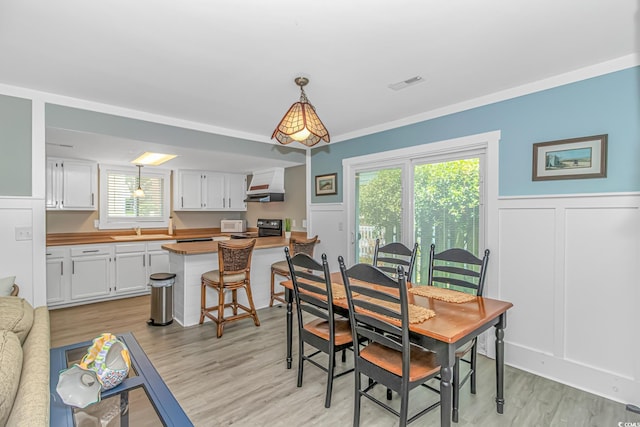 4309 Beverly Ct, North Myrtle Beach, SC 29582 - dining area featuring healthy amount of natural light, wainscoting, light wood-style flooring, and a decorative wall