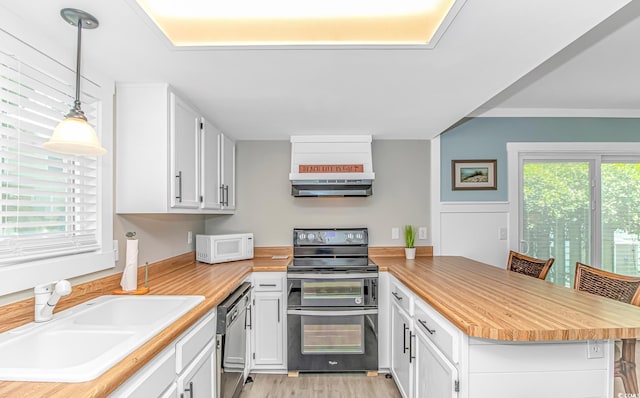 4309 Beverly Ct, North Myrtle Beach, SC 29582 - kitchen featuring stainless steel appliances, a peninsula, plenty of natural light, and wall chimney range hood